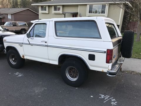 1985 Ford Bronco - This white 1985 Ford Bronco is seen from the rear quarter, a spare tire mounted on the tailgate.