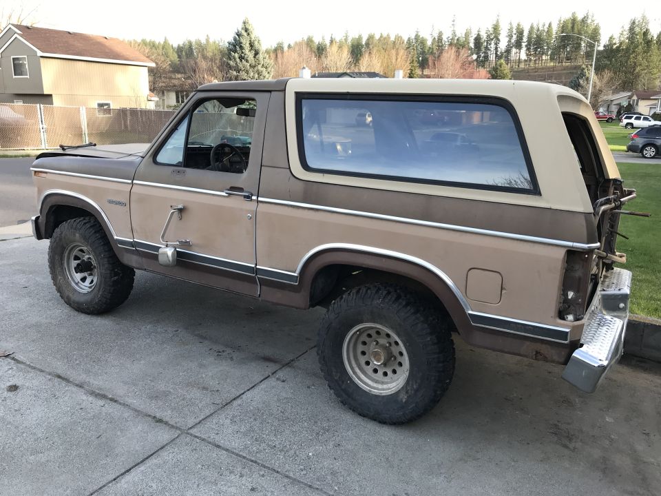 1985 Ford Bronco parked on a driveway, side view. Two-tone brown and tan paint, removable hardtop