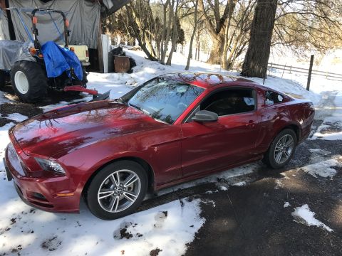 2014 Ford Mustang - A red 2014 Ford Mustang coupe sits in a snowy driveway next to a covered tractor.