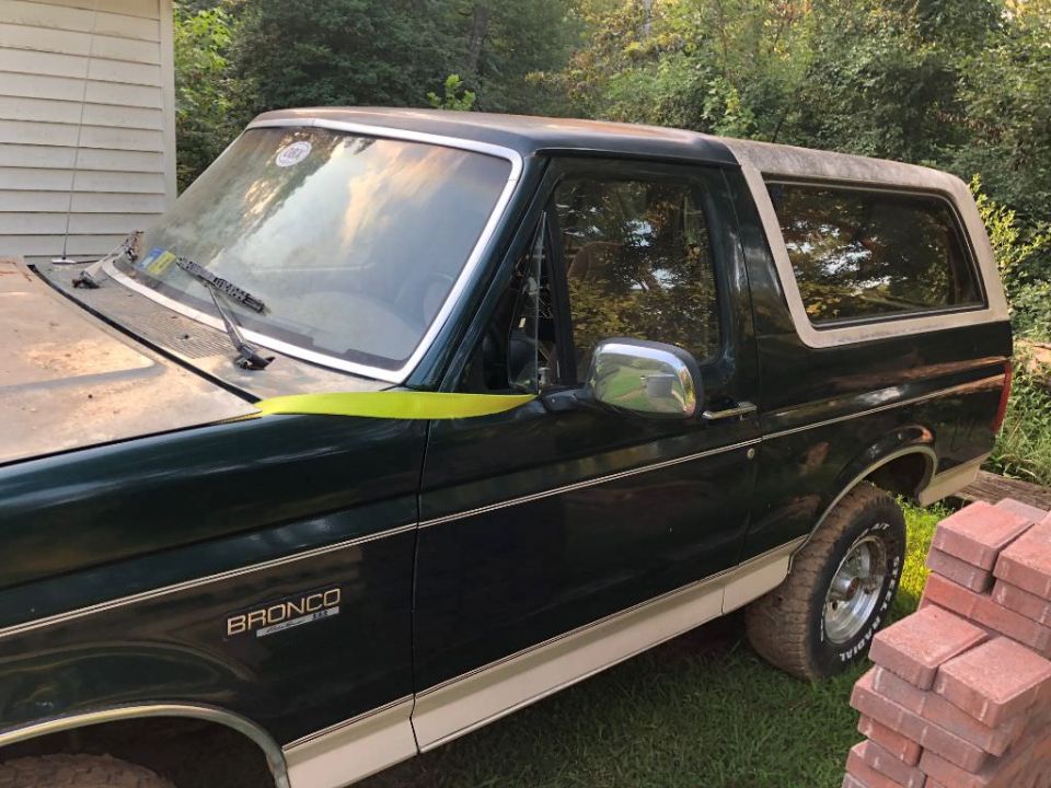 Dark green 1993 Ford Bronco with white top, side view