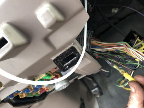 1995 Ford Bronco - A close-up view of a vehicle's interior wiring harness, with a hand connecting a yellow wire.