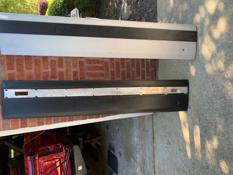 1994 Ford Bronco - Two vehicle door trim pieces are laid out on a concrete and brick surface.