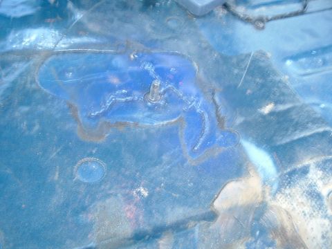 1989 Ford Bronco - Close-up of a blue vehicle floorpan showing rust damage and a single bolt.