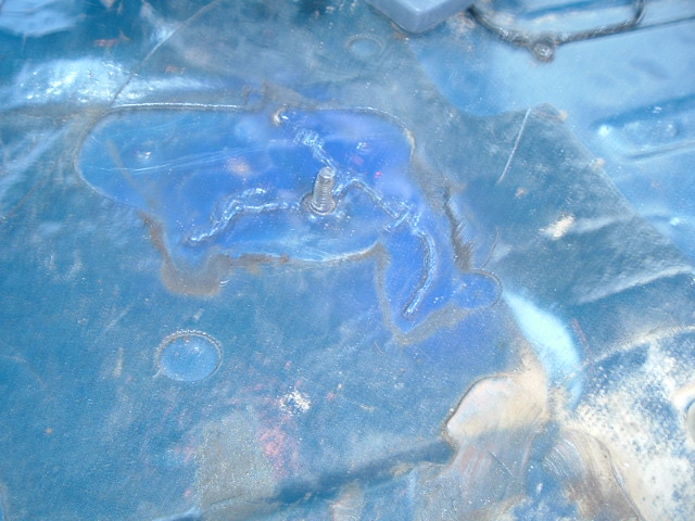 Blue floor under clear plastic with a threaded stud and rust staining