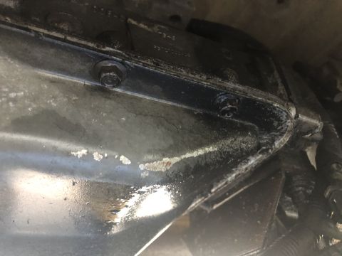 1995 Ford Bronco - Close-up view of a vehicle's transmission pan, showing bolts and some surface wear.
