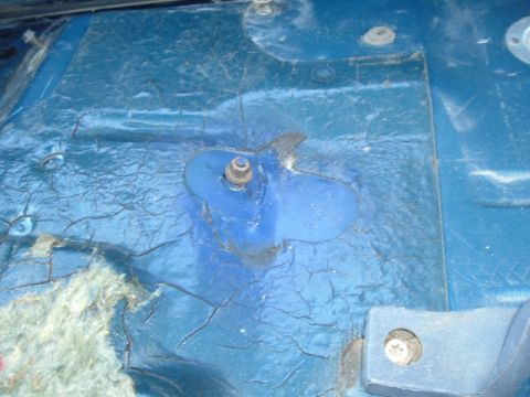 1989 Ford Bronco - Cracked blue paint on a vehicle's floor pan with visible rust and insulation.