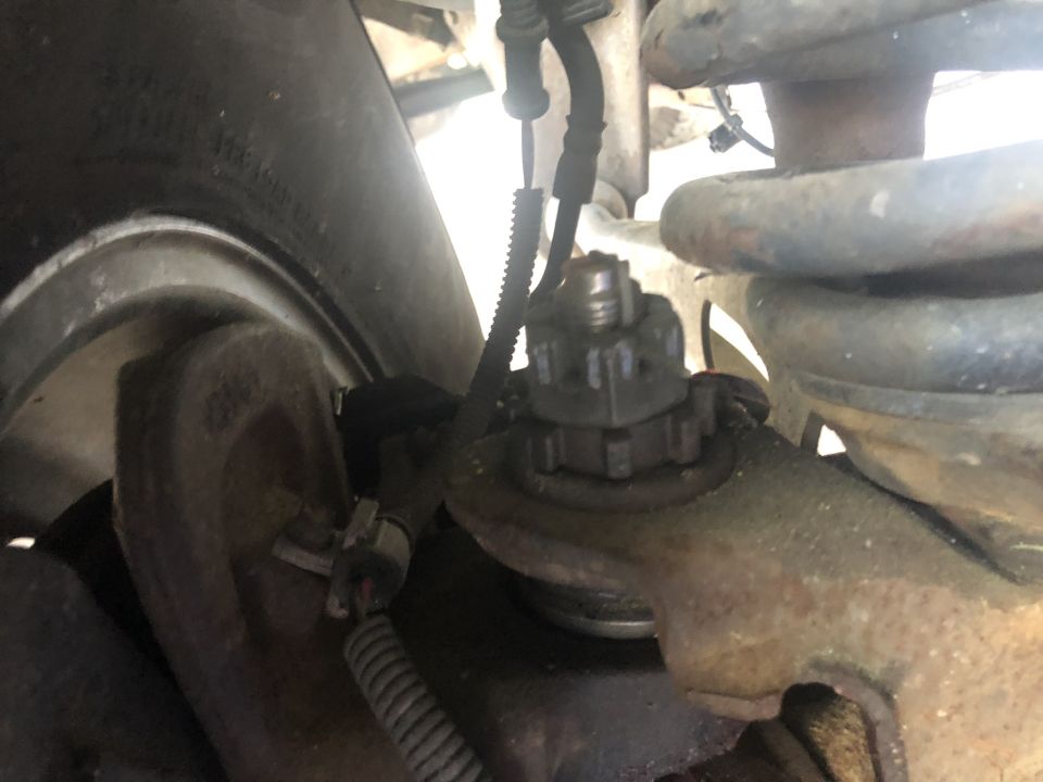 Close-up of vehicle suspension, ball joint, and tire.