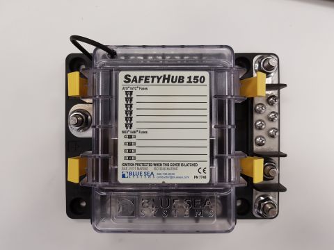 1978 Ford Bronco - A Blue Sea Systems SafetyHub 150 fuse block is shown mounted on a black backing plate. The fuse block has a clear protective cover with lab…