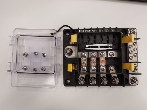 1978 Ford Bronco - A black fuse box with a clear plastic cover is shown open, revealing multiple fuse slots and screw terminals. Three fuses are visible, labe…