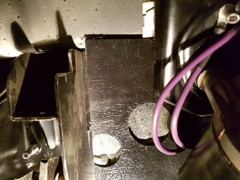 1978 Ford Bronco - A close-up view of the interior of a 1978 Ford Bronco shows a black textured surface with two circular felt pads and purple wiring. A metal…