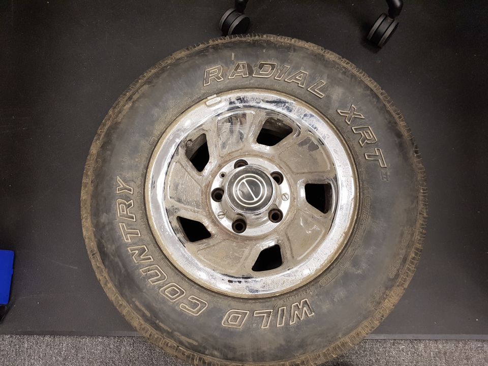 Tire and chrome rim with WILD COUNTRY RADIAL XRT text