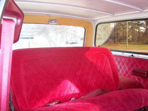 1979 Ford Bronco - The interior features quilted red velour upholstery and a view of the outdoors through the windows.