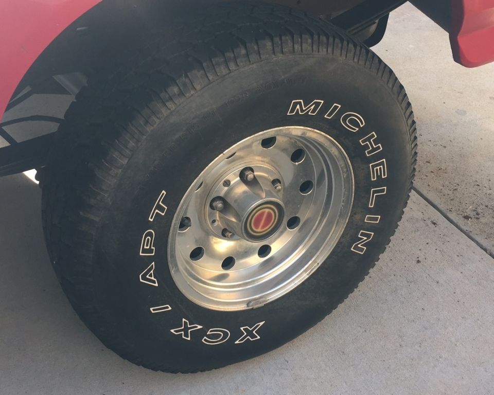 Close-up of a red vehicle's Michelin APT XCX tire and chrome wheel.