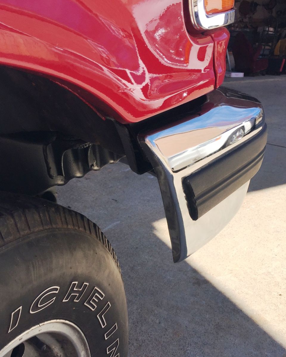 Red vehicle fender, chrome bumper, and tire detail