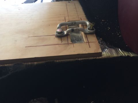 1994 Ford Bronco - A wooden panel with a metal tie-down anchor bolted to it is installed on the floor of a vehicle, likely for securing cargo.