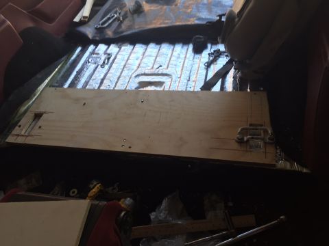 1994 Ford Bronco - A wooden panel is being installed on the floor of a vehicle, likely for a custom storage solution. Hardware and tools are visible in the su…