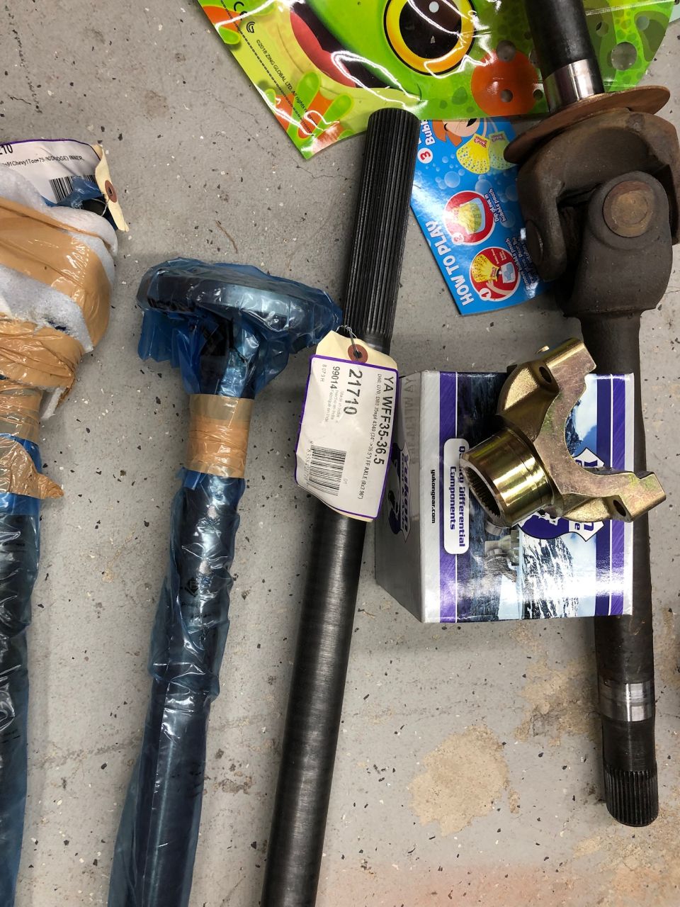 Automotive axle shafts and a universal joint on a concrete floor.