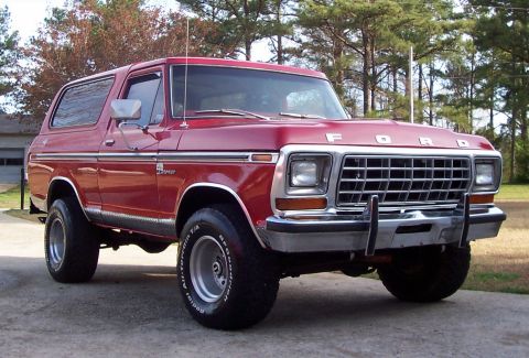 1979 Ford Bronco - This red Ford Bronco features a prominent chrome grille and side trim, with off-road tires.