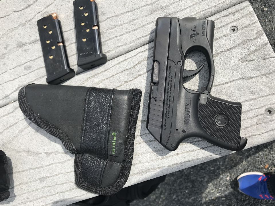 Black Ruger LCP pistol, two magazines, and a black holster on a wooden surface.