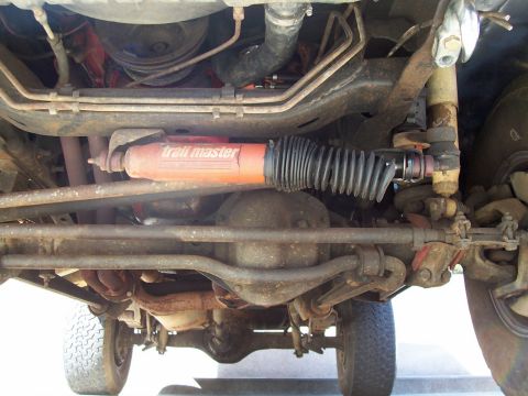 1979 Ford Bronco - Undercarriage view shows a Trail Master shock absorber and steering linkage, with visible Supermotors.net watermark.