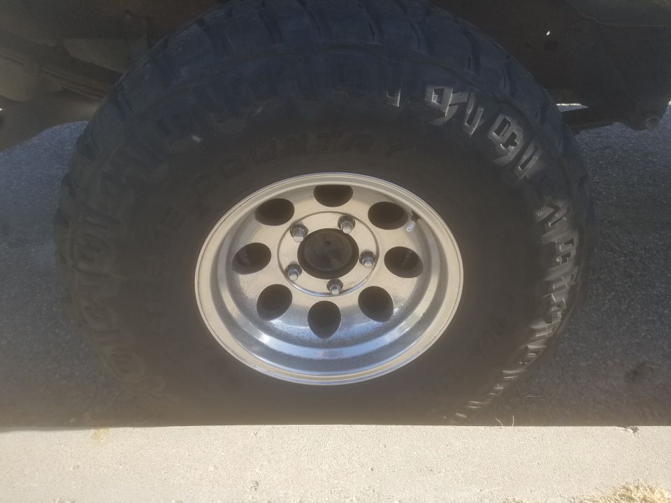 Close-up of an off-road tire and silver wheel on a vehicle.