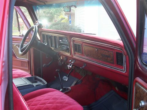 1979 Ford Bronco - Interior view of a 1979 Ford Bronco, showing red quilted upholstery and wood-grain dash accents.
