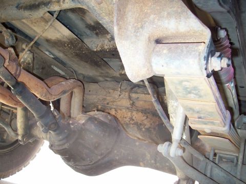 1979 Ford Bronco - The underside of a vehicle reveals its suspension and drivetrain components.