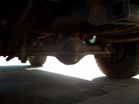 1979 Ford Bronco - A low-angle shot reveals the rear axle and suspension components of a vehicle.