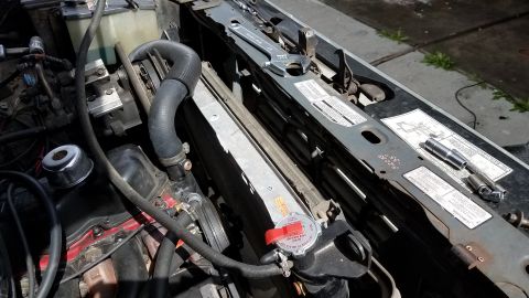 1985 Ford Bronco - The engine bay of a vehicle, likely a 1985 Ford Bronco, is shown with the hood open. A radiator, hoses, and engine components are visible,…