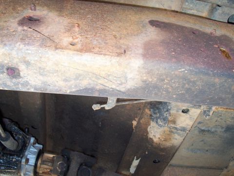 1979 Ford Bronco - Vehicle underbody shows significant rust on the frame and a visible driveshaft.