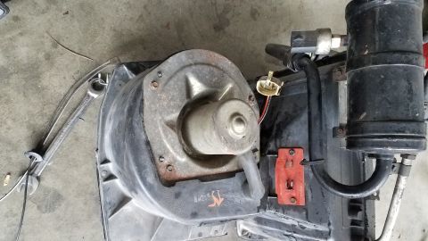 1985 Ford Bronco - A blower motor assembly is shown, likely from a vehicle's air conditioning system, with associated hoses and wiring.