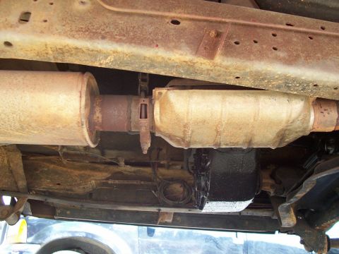 1979 Ford Bronco - The underside of a vehicle shows the exhaust system and transmission components.
