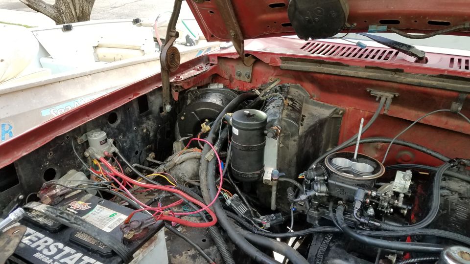 Engine bay with carburetor, battery, and wiring visible
