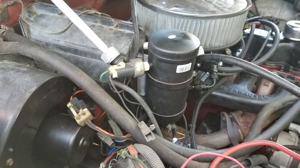Close-up of 1985 Ford Bronco engine bay showing AC receiver-drier, hoses, and wiring.
