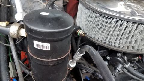 1985 Ford Bronco - A close-up view of the engine bay of a 1985 Ford Bronco, focusing on the air conditioning receiver-drier and a chrome air filter housing. T…