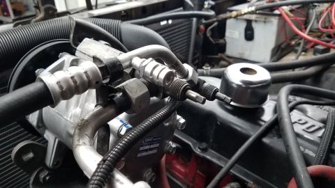 1985 Ford Bronco - A close-up view of the air conditioning compressor and associated lines in an engine bay. The compressor has a UAC logo visible on its hous…