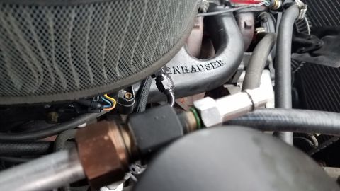 1985 Ford Bronco - A close-up view of engine components, including a black air filter housing, a black intake manifold with "INHAUSER" text, and various hoses…