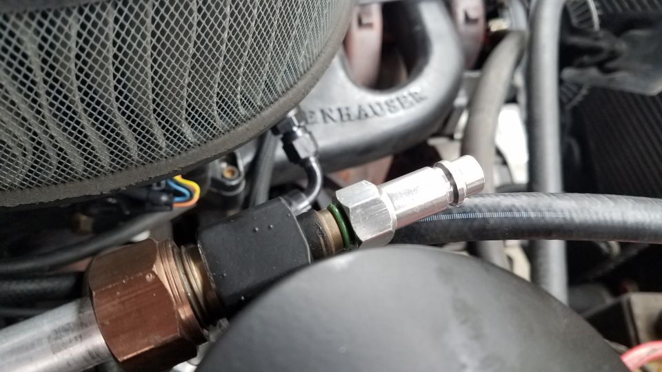Engine bay with air filter, exhaust manifold, and AC lines.