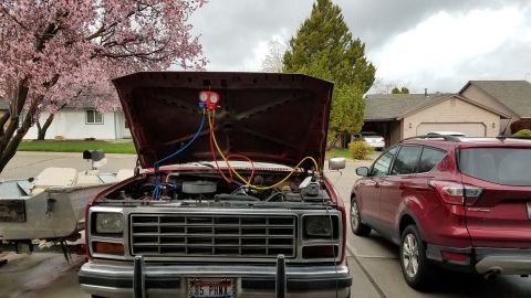 1985 Ford Bronco - A red 1985 Ford Bronco with its hood open is parked in a driveway, connected to an air conditioning manifold gauge set. A red Ford Escape i…