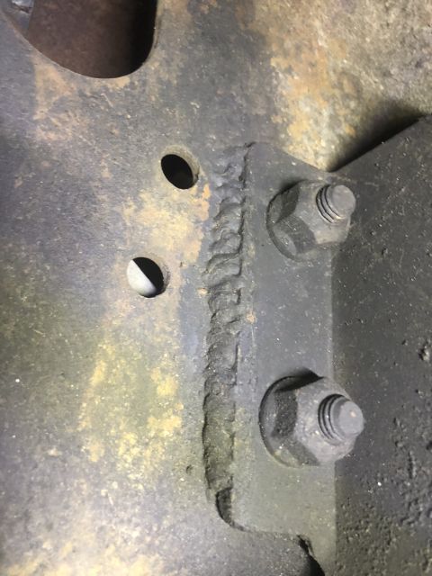 1995 Ford Bronco - A close-up view shows a welded metal bracket with two bolts securing it to a vehicle frame. The metal appears rusty and dirty, with visible…