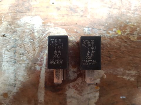 1978 Ford Bronco - Two automotive relays are shown side-by-side on a wooden surface. Both relays have identical markings indicating their electrical function…