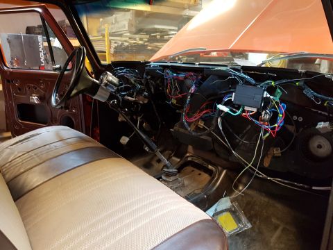 1978 Ford Bronco - The interior of a 1978 Ford Bronco shows exposed wiring and an open orange hood, indicating ongoing work.