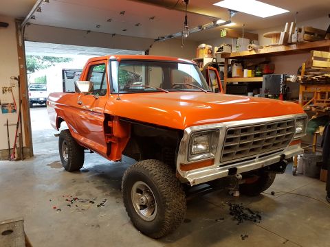 1978 Ford Bronco - Orange Ford F-Series truck undergoing repairs in a garage with the doors off.