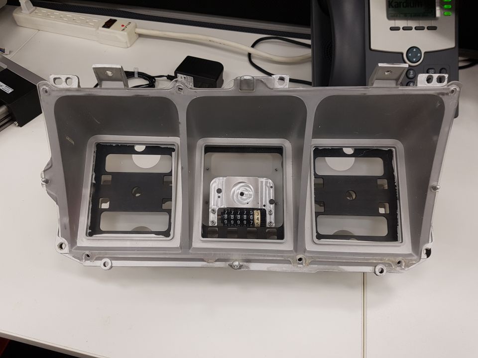 Dashboard housing with three openings for gauges and a central odometer mechanism