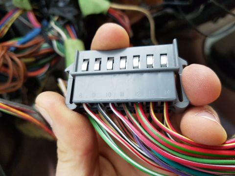 1978 Ford Bronco - Close-up of a vehicle's wiring harness connector, showing numbered ports and various colored wires being held by fingers.