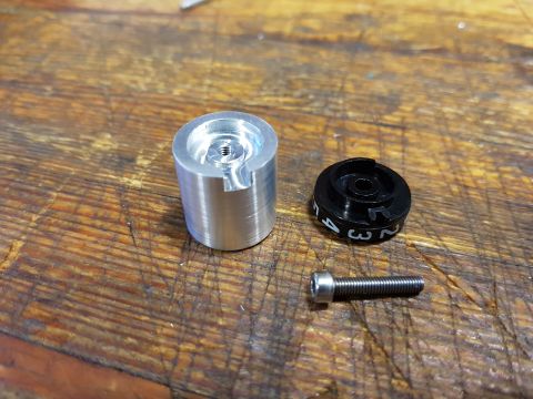1978 Ford Bronco - Close-up of disassembled metal components, including a machined aluminum piece and a black dial with numbers.