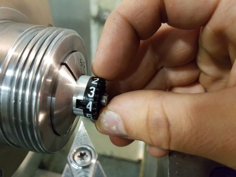 1978 Ford Bronco - A hand adjusts a numbered dial on a mechanical part, likely in a workshop setting.