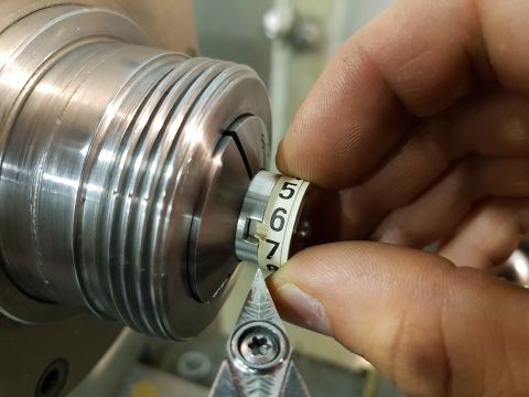 1978 Ford Bronco - A hand adjusts a numbered ring on a machined metal component, likely during a manufacturing or repair process.