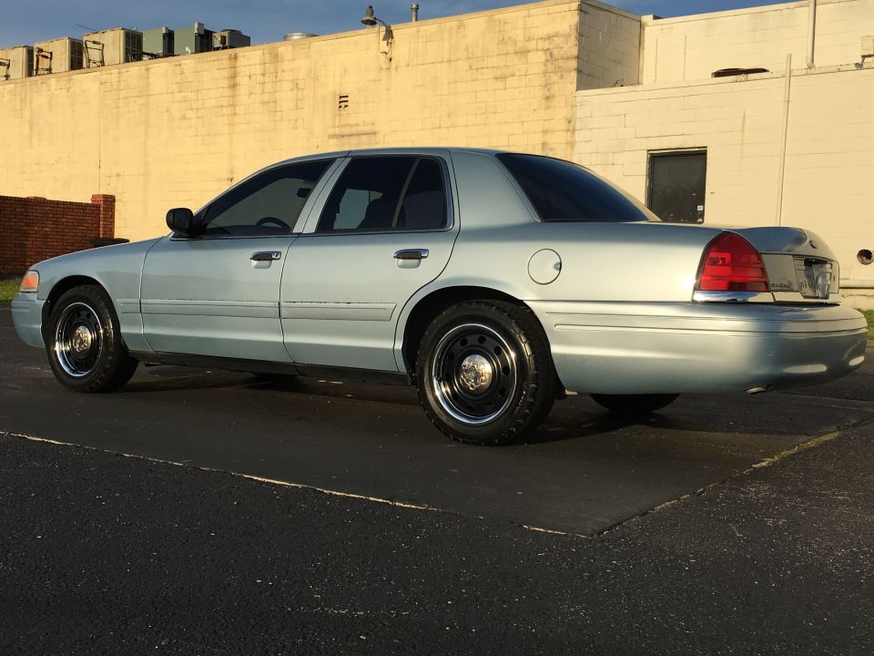 Light blue 2006 Ford Crown Victoria sedan, rear quarter view, steel wheels, minor body damage on rear bumper