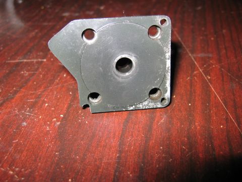 1993 Ford F-150 - A metal bracket with a central hole and surrounding bolt holes is shown on a wooden table.